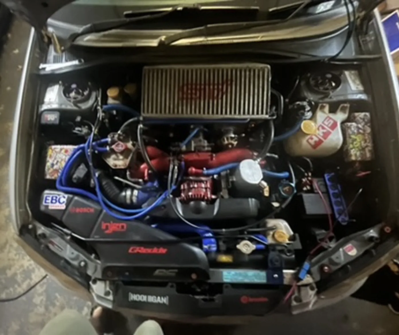 Modified Subaru engine bay with blue hoses and an intercooler